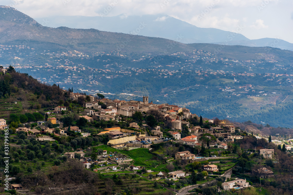A close-up panoramic view of the old French town Saint-Jeannet and its medieval architecture with the low Alps mountains hills in the background (Provence / Riviera / Côte d'Azur)