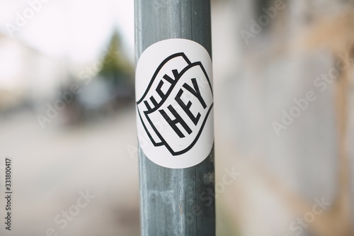 Closeup of hey written on a sticker on a pipe under the lights with a blurry background photo