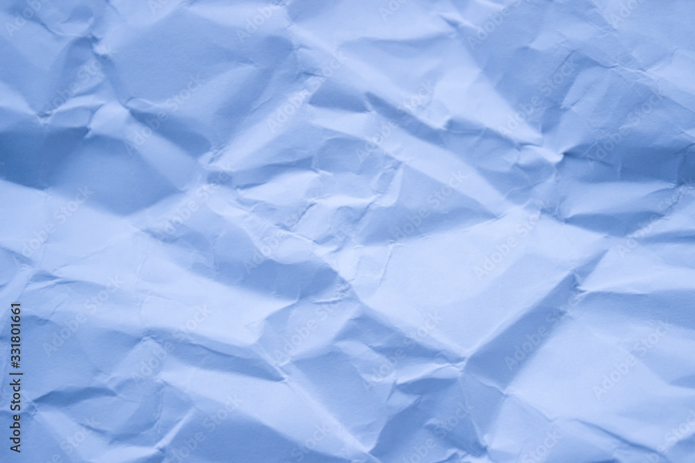 Fototapeta premium A sheet of white paper crumpled and then straightened Selective focus. Toned in blue color