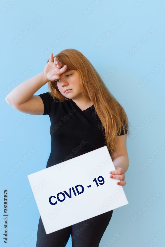 Young woman of Caucasian appearance suffering with a headache and fever, she is touching her head, concept of symptoms covid-19, on an isolated blue background, summary place for text Young woman of Caucasian appearance suffering with a headache and fever, she is touching her head, concept of symptoms covid-19, on an isolated blue background, summary place for text