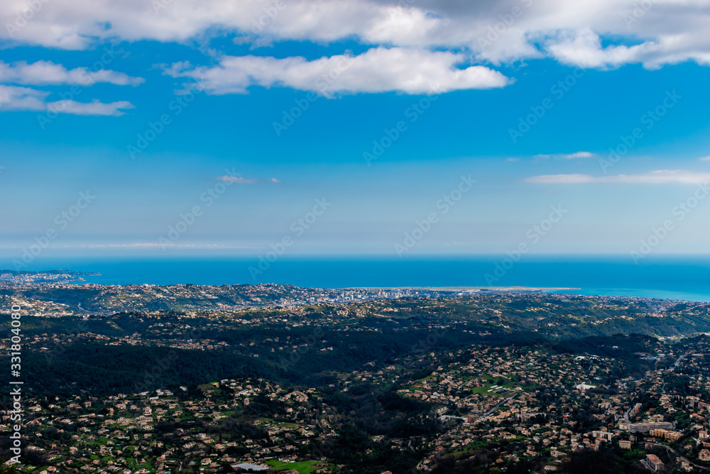A wide / high angle panoramic view of buildings of several towns covering the low Alps mountains hills and the Mediterranean Sea coastline (French Côte d'Azur/ Provence/ Riviera)