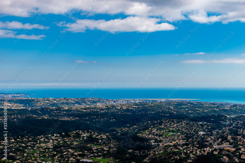 A wide / high angle panoramic view of buildings of several towns covering the low Alps mountains hills and the Mediterranean Sea coastline (French Côte d'Azur/ Provence/ Riviera) A wide / high angle panoramic view of buildings of several towns covering the low Alps mountains hills and the Mediterranean Sea coastline (French Côte d'Azur/ Provence/ Riviera)