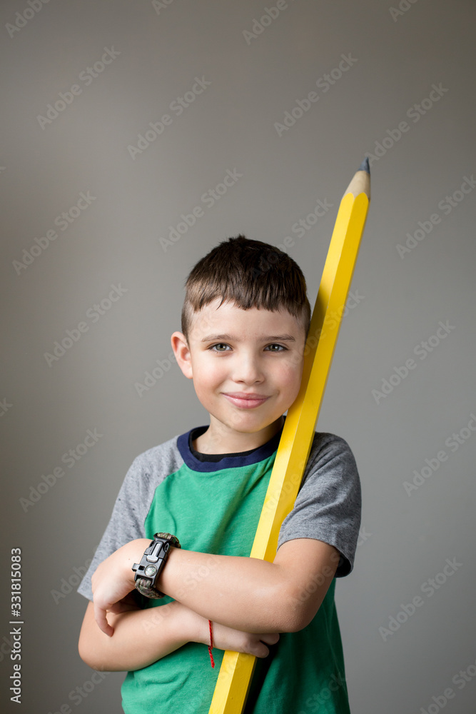 Cute caucasian student holding a big yellow pencil. The concept of home schooling, creative writing, language learning. Cute caucasian student holding a big yellow pencil. The concept of home schooling, creative writing, language learning.
