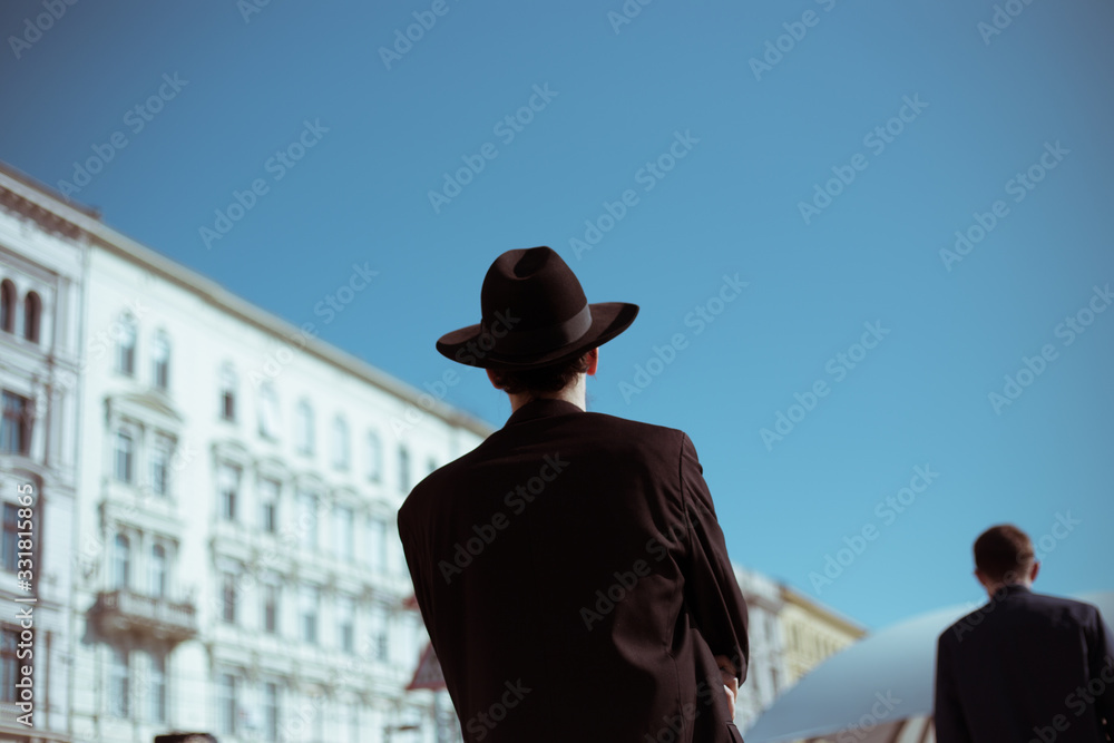 Orthodox Jew from the back with a hat in the afternoon