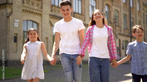 Front view of happy family of four walking and holding hands at city park. happy family on vakation with their son and daughter. Family love concept. photo