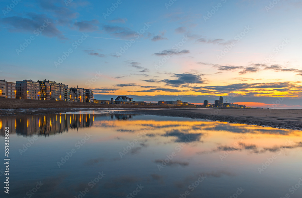 Sunset along the North Sea beach of Ostend city (Oostende in Flemish) with a skyline reflection, West Flanders, Belgium.