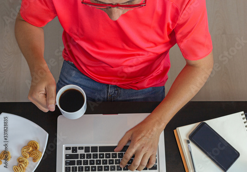 Man drinking coffee and working with his laptop at home