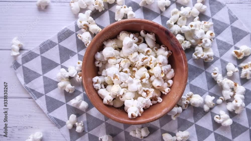 popcorn in a bowl and spilling on table popcorn in a bowl and spilling on table