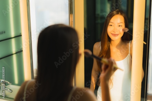 Portrait beautiful young asian woman make up with cosmetic powder and lipstick on her face facial in bathroom