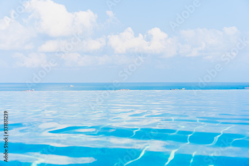 Beautiful infinity outdoor swimming pool with sea ocean view around white cloud blue sky