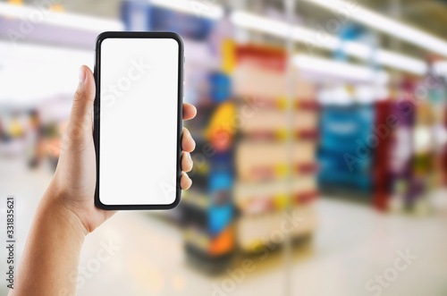 hand holding mobile white screen on Supermarket store blur background