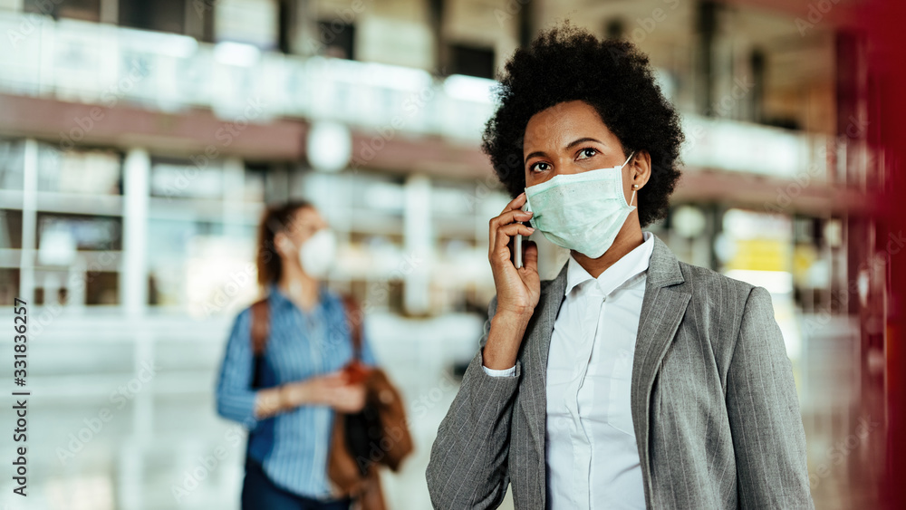 African American businesswoman wearing protective mask while making a phone call at the airport.