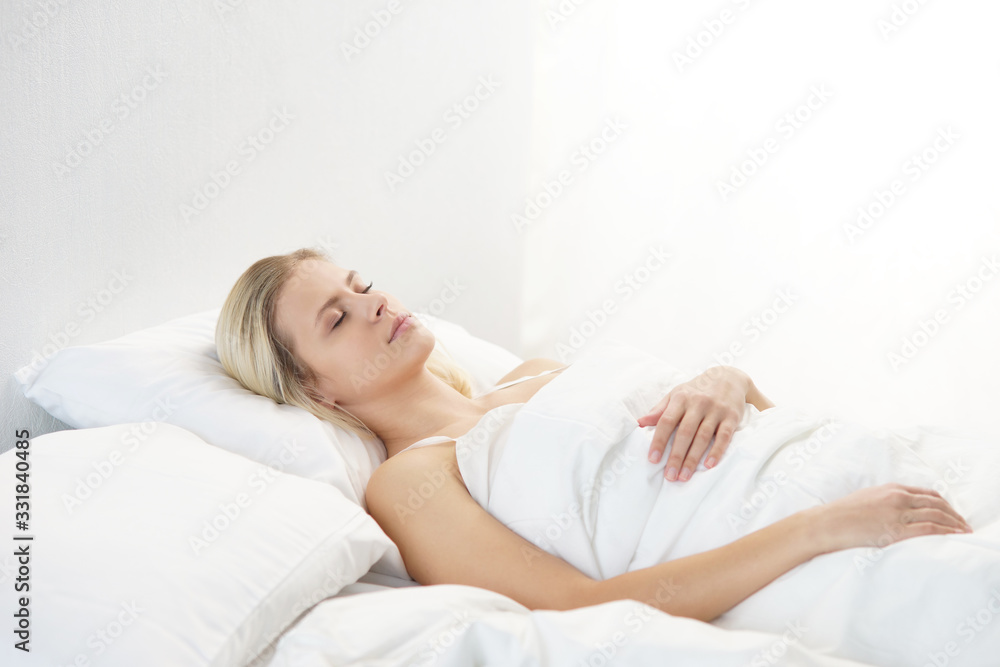 Young woman lying in the bed. Beautiful blond sleeping girl. Morning in the bedroom, daylight from the window. Health and rest. Young woman lying in the bed. Beautiful blond sleeping girl. Morning in the bedroom, daylight from the window. Health and rest.