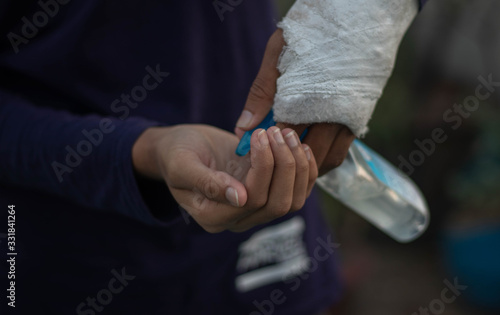 Closeup of a coronavirus infected man disinfecting his hands with alcohol hand sanitizer from a bottle.Selective focus