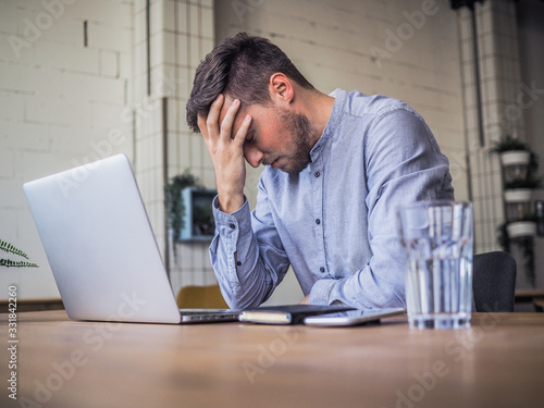 Fotografía worried and disappointed remote online working man in casual outfit with laptop