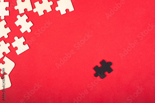 wooden white and black puzzles on a red background close-up top view. outcast antisocial leader differ from others children's educational toy