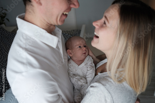 Smiling mother and father holding their newborn baby daughter at home © Make_story Studio