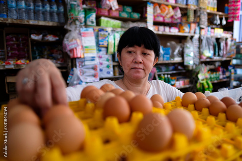 Asian Indonesian women arranging eggs inside small local family-owned business store, locally called warung. Selective Focus.