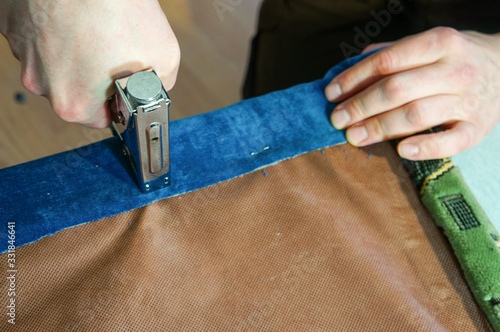 man sheathes furniture, nails fabric with a stapler photo