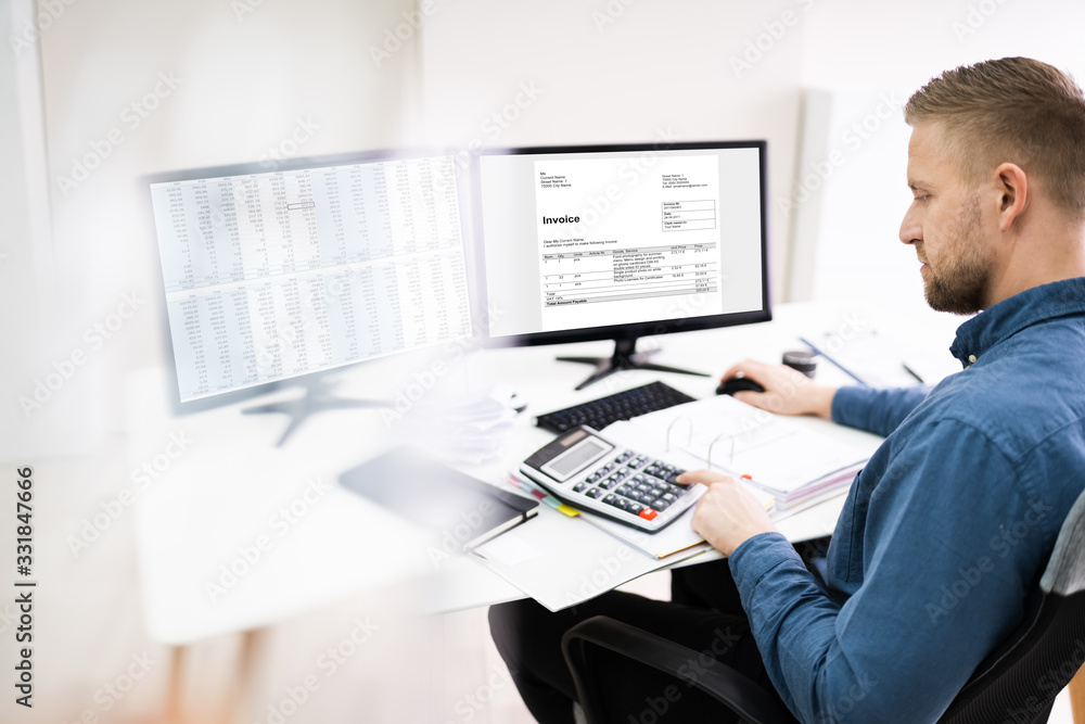 Young Businessman Calculating Bill In Office Young Businessman Calculating Bill In Office