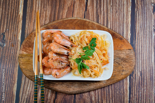 Udon noodles and fried cocktail prawns on a plate.