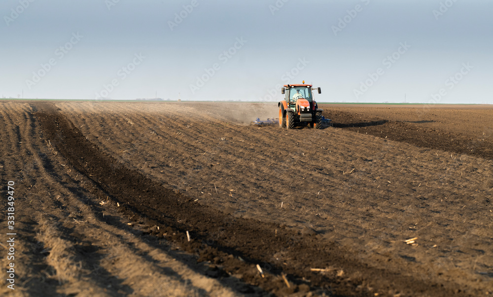 Fototapeta premium Tractor is preparing the land at dusk