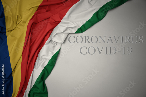 waving national flag of seychelles on a gray background with text coronavirus covid-19 . concept.