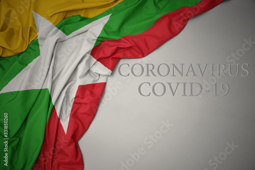 waving national flag of myanmar on a gray background with text coronavirus covid-19 . concept.