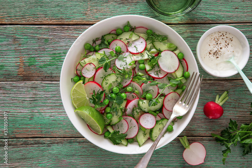 Fresh radish, cucumber and green peas salad in white bowl