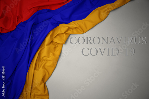 waving national flag of armenia on a gray background with text coronavirus covid-19 . concept.