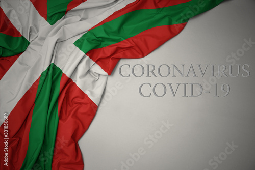 waving national flag of basque country on a gray background with text coronavirus covid-19 . concept.