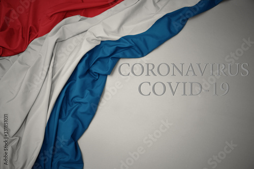 waving national flag of luxembourg on a gray background with text coronavirus covid-19 . concept.