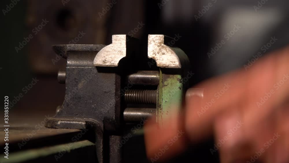The hand squeezes small engineering vice.That is fixed on the table The hand squeezes small engineering vice.That is fixed on the table