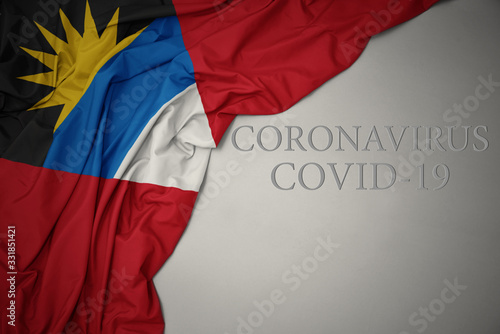 waving national flag of antigua and barbuda on a gray background with text coronavirus covid-19 . concept.