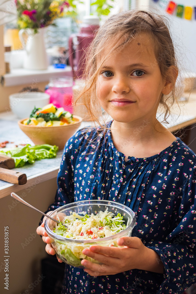 Little young vegan, vegetarian girl kid with food in hands. Healthy eating. Family health care concept. Fresh detox cabbage salad Little young vegan, vegetarian girl kid with food in hands. Healthy eating. Family health care concept. Fresh detox cabbage salad