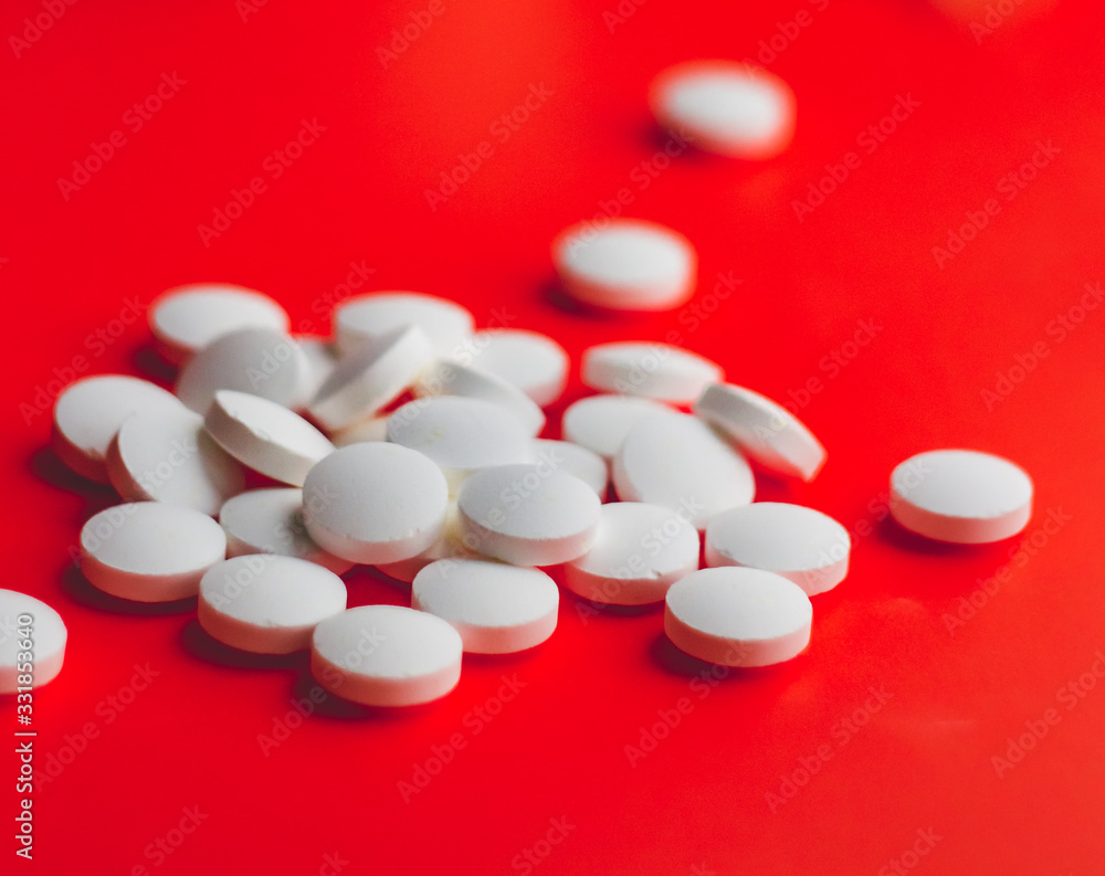 a handful of white pills in the foreground on a bright color background a handful of white pills in the foreground on a bright color background