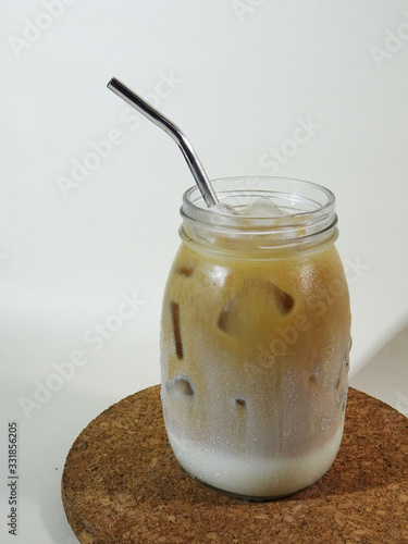 A Glass of Ice Coffee Latte with Metal Straw on Cork Coaster