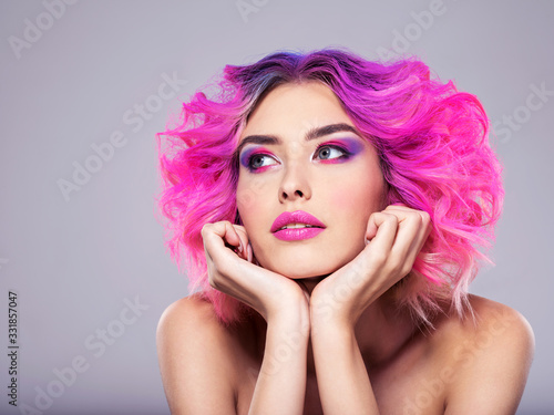 Portrait of beautiful young woman with bright pink makeup. Beautiful blonde with bright pink lipstick on her lips. Pretty girl with vivid hair. Blonde with brightly colored hair. Bright eye makeup.