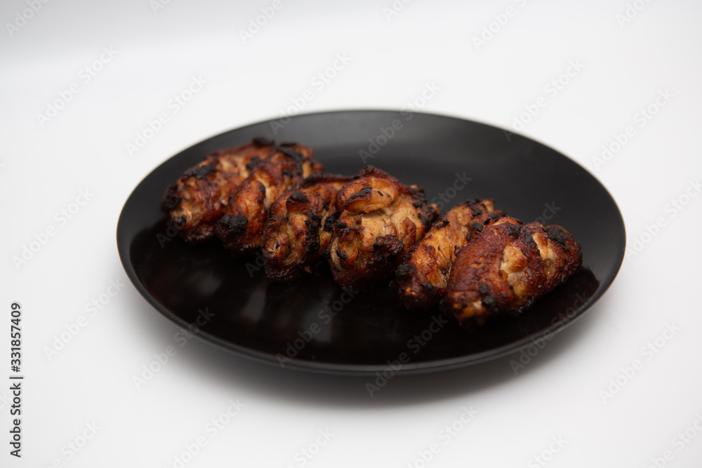 barbecue chicken wings close up on wooden tray shot with selective focus In the black plate, white background