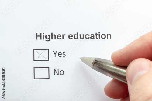 Higher education - yes. A pen in a male hand. Checklist concept.