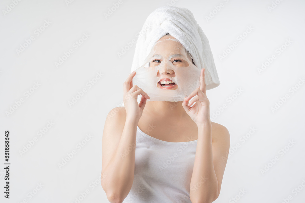 Asian woman is facial mask sheet . She is happy and surprise.