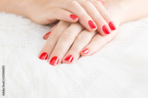 Beautiful woman hands with red nails on light white furry background. Manicure beauty salon concept. Front view. Closeup.