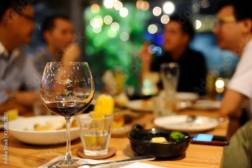 Bangkok / Thailand - Dec 31 2018 : Glass of wine and a glass of water were put on the table in a restaurant, blurred background is a group of friends meet. with beautiful bokeh.
