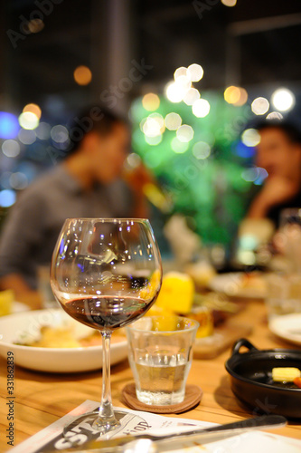 Glass of wine and a glass of water were put on the table in a restaurant, blurred background is a group of friends meet. with beautiful bokeh.