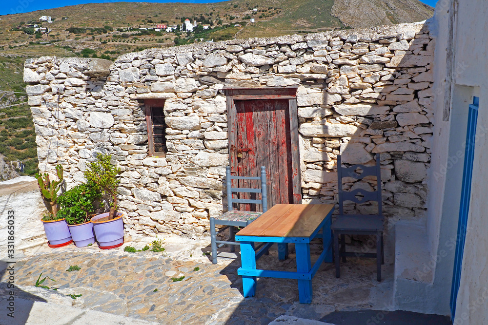 One of the charms of the Greek islands of Cyclades, are the small terraces with their colorful tables and chairs on the ground floor of the stone houses of the narrow cobbled streets