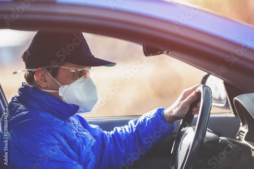 A man in medical face mask and safety glasses during an epidemic in the car