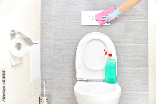A woman in gloves cleans the bathroom. 