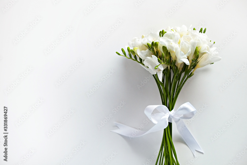 Delicate freesia bouquet on white background as spring holiday season symbol concept. Close up shot of fresh flowers with a lot of copy space for text. Minimalistic background.