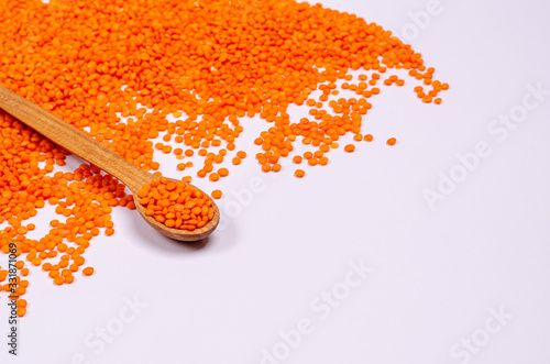 Dry orange lentils for vegans in a wooden spoon on a white background, copy space, place for text.