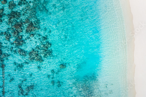 Sand beach aerial, top view of a beautiful sand coral beach aerial shot with the blue waves rolling into the shore. Tranquility and meditation background